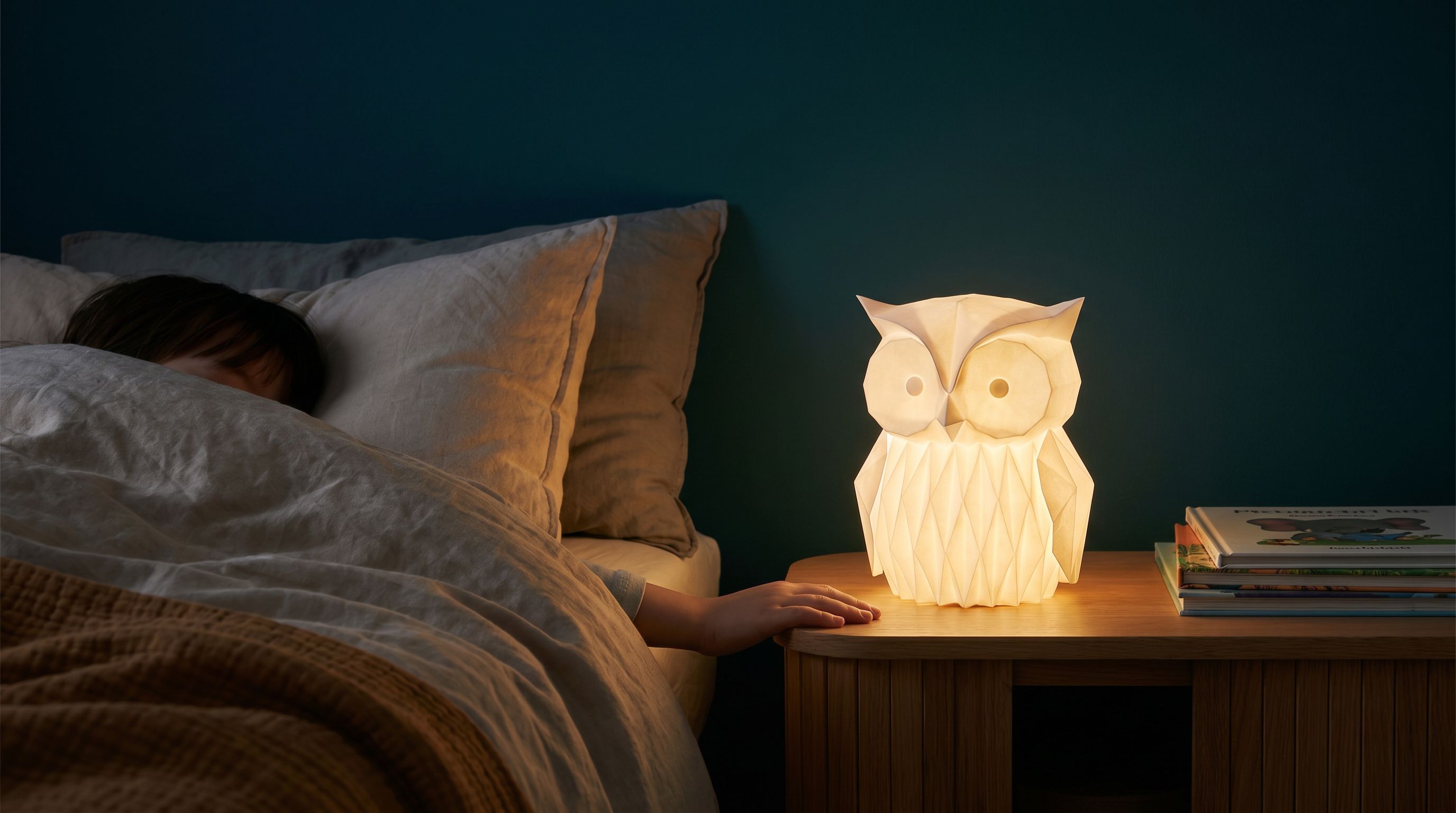 Réveil-sculpture posé sur une table de chevet, lit par une lumière chaude — chambre d'enfant la nuit